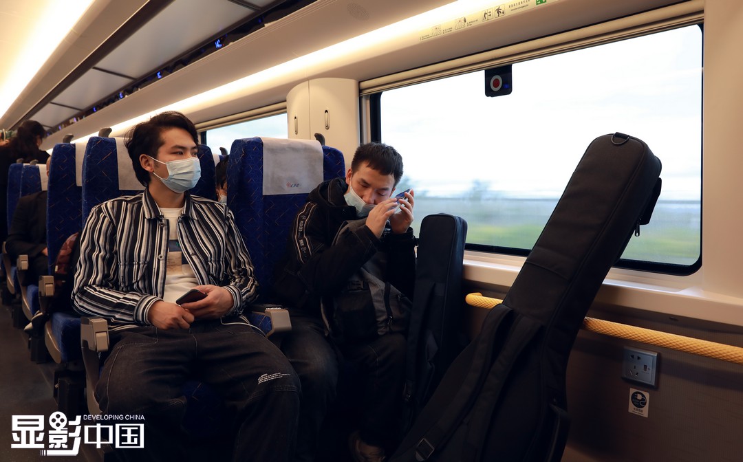　樂隊一起坐高鐵出行去畢節演出，彭萬海幫他們找到座位，楊林在網購，他打算為家裏買一個浴霸（11月8日攝）。新華網 盧志佳 攝